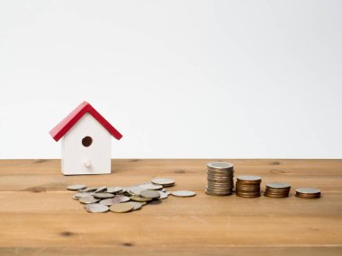 Kırmızı house ile ahşap arka plan üzerinde büyüyen para sikke yığını. 