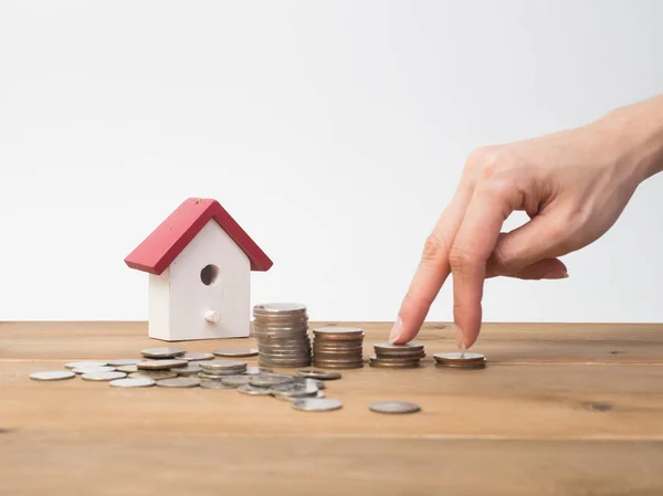 Money coins stack growing with red house on wood background