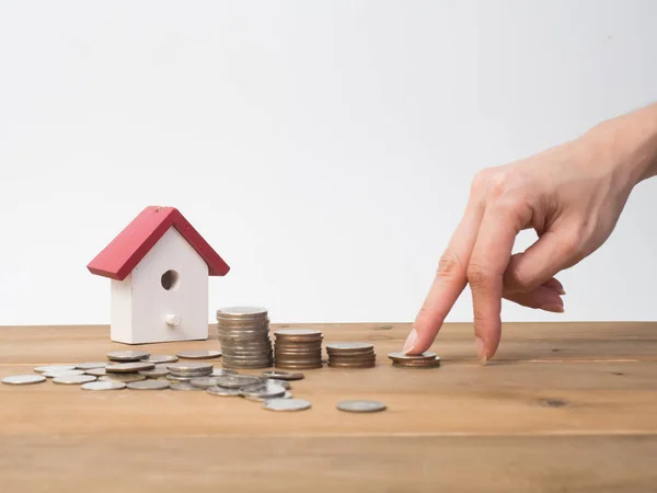 Money coins stack growing with red house on wood background.