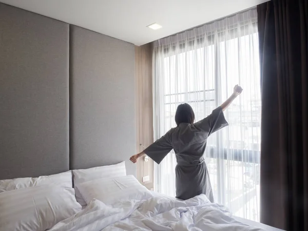 Woman stretching in bed after waking up, back view — Stock Photo, Image