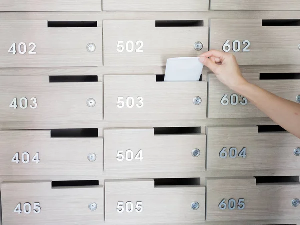 Närbild av personens hand. hand ta bort ett brev från postlåda i entréhallen i ett hyreshus — Stockfoto