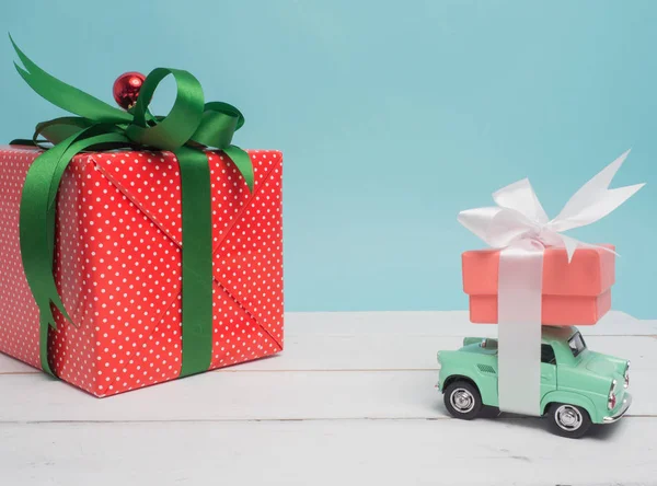 Eski model araba Noel ve yeni yıl ve Sevgililer günü için bir hediye kutusu renk arka plan ve üst ahşap masa üzerinde taşırlar. Dekorasyon aşk kalp .