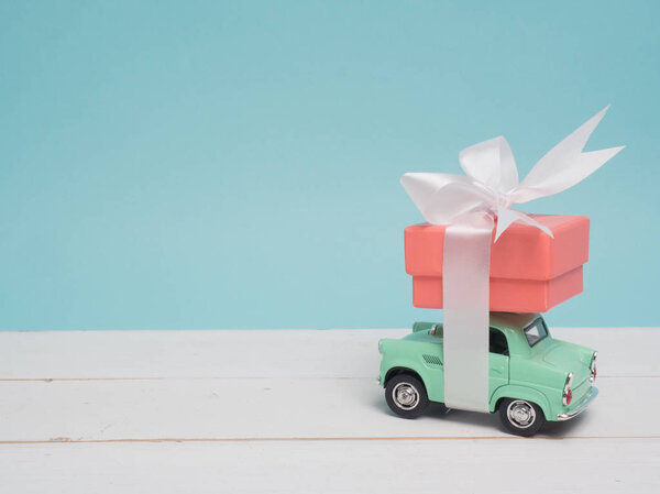 Vintage car carry a  gift box on color background and top wood table for Christmas and The New Year and Valentine's day .Decoration love heart .