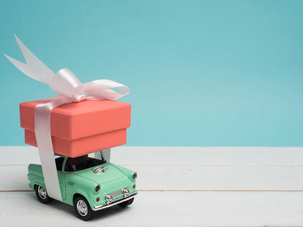 Eski model araba Noel ve yeni yıl ve Sevgililer günü için bir hediye kutusu renk arka plan ve üst ahşap masa üzerinde taşırlar. Dekorasyon aşk kalp .