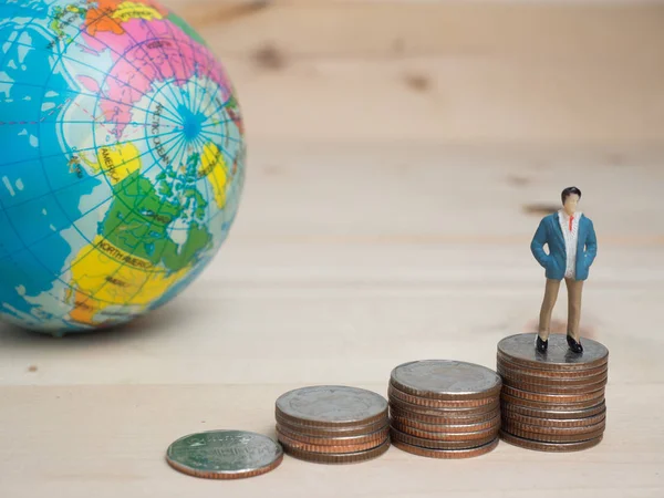 Para ve iş kavramı. İşadamı küçük rakam ayakta sikke yığını üstünde ve sonraki sikke yığını arasında bu merdiven ile dört gözle.