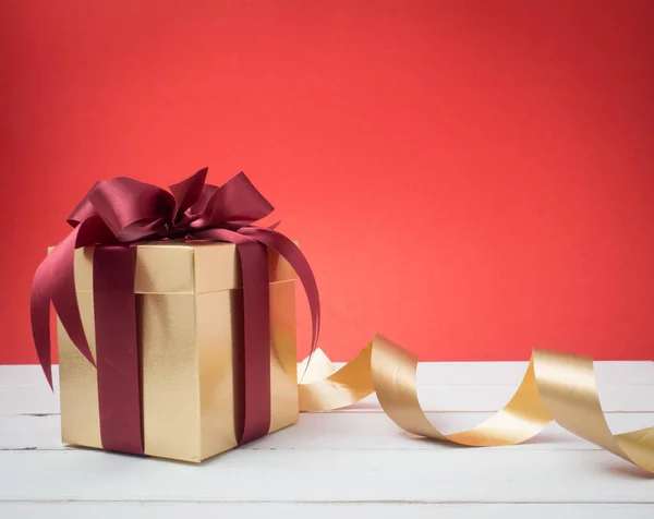 Festival de San Valentín, Año Nuevo Caja de regalo de oro con cinta roja. Rojo. —  Fotos de Stock