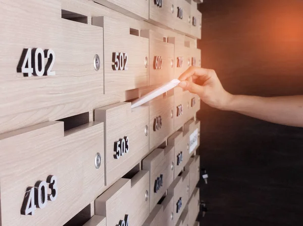 Närbild av personens hand. hand ta bort ett brev från postlåda i entréhallen i ett hyreshus — Stockfoto