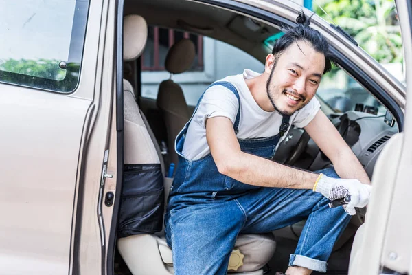 Fixing car engine in automobile repair garage. Handsome mechanic