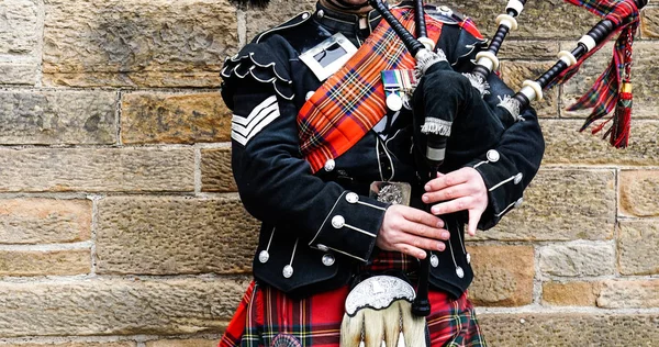 エディンバラ スコットランド 2018 スコットランド笛吹きは石の壁の前に伝統的な赤と黒のタータン ドレス スタンドに身を包んだ エジンバラ スコットランドで最も人気のある観光都市 — ストック写真