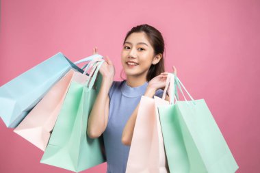 Pembe pastel arka plan üzerinde oturan Asyalı güzel genç kadın. Seh