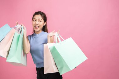 Pembe pastel arka plan üzerinde oturan Asyalı güzel genç kadın. Seh