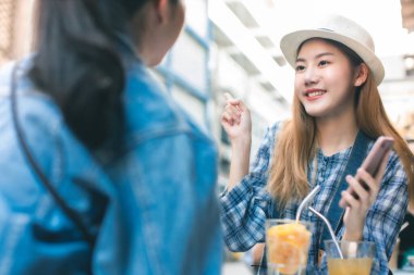 Genç Asyalı bayan arkadaşlar Bangkok 'ta tatil yapıyor ve sokak yemeği yiyorlar. Asyalı kadın rahatlar ve mutluluk duygusuyla konuşur. Arkadaşıyla cep telefonuyla fotoğraf çeker..