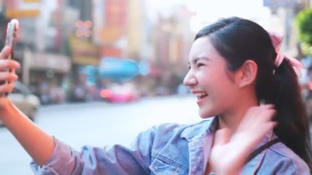 笑顔若いアジアの女性は中国の町バンコクを旅行します スマートフォンのショッピングをオンラインで利用し路上生活をしながら笑顔で — ストック動画