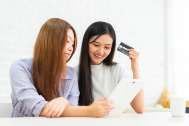 İnternet sosyal medya yaşamında komik videolar izlerken gülen mutlu en iyi arkadaşlar. Genç Asyalı kadın evde laptop ve kredi kartıyla online alışveriş yapıyor..