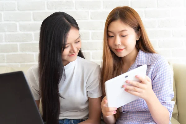 Happy best friends laughing during watching funny videos on internet  social media life . Young Asian female  doing online shopping through laptop and credit card at home.