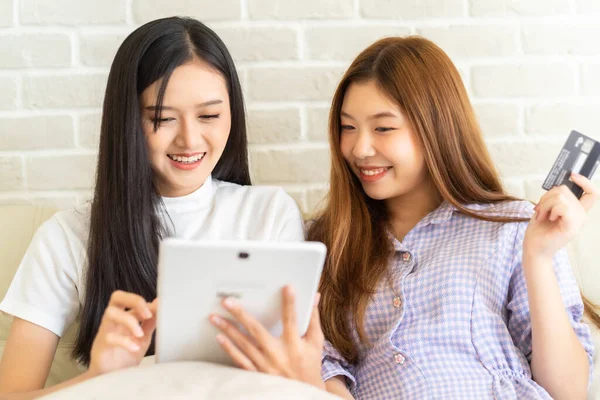 İnternet sosyal medya yaşamında komik videolar izlerken gülen mutlu en iyi arkadaşlar. Genç Asyalı kadın evde laptop ve kredi kartıyla online alışveriş yapıyor..