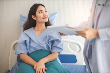 Tıp ve sağlık hizmetleri kavramı. Asyalı doktor hasta kadını hastaneye götürüyor. Doktor ya da hemşire koruma maskesi takıyor. Enfeksiyonu kontrol ediyor. .