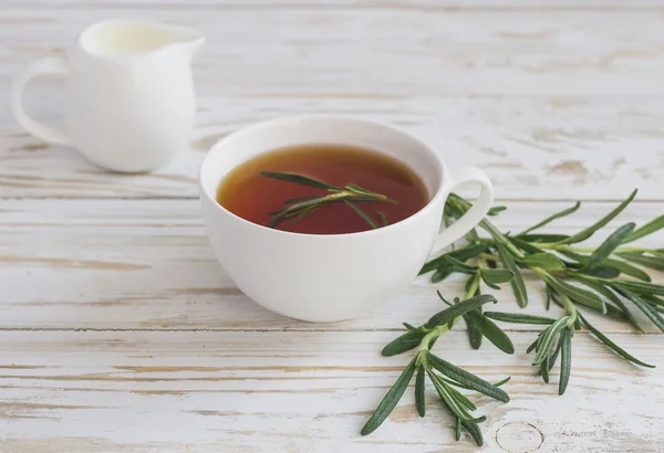 Pot de thé et de lait au romarin sur table en bois . — Photo