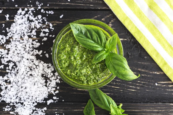 Pesto sauce in glass jar, sea salt and basil leaves