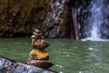 Şelale yakınındaki taş denge. Uyum kavramı.