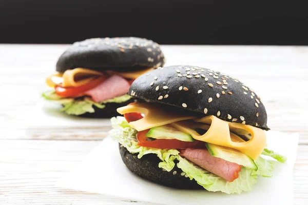 Hamburger nero con prosciutto, formaggio, cetriolo, pomodoro e lattuga — Foto Stock
