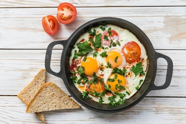 Pan of fried eggs, tomatoes and parsley with bread — Stock Photo, Image