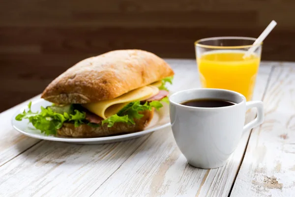 Chiabatta sandwich, kopp kaffe och apelsinjuice juice — Stockfoto