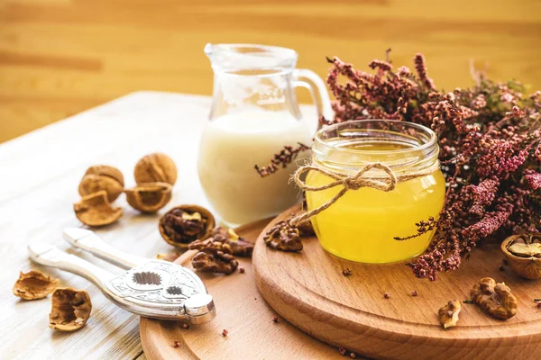 Melk, heather bloemen, walnoten en honing. Houten tafel. — Stockfoto