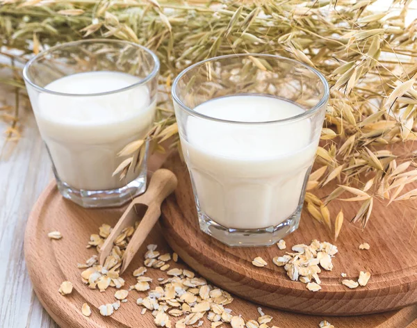Two glasses of milk and oat spikelets on rustic table — Stock Photo, Image