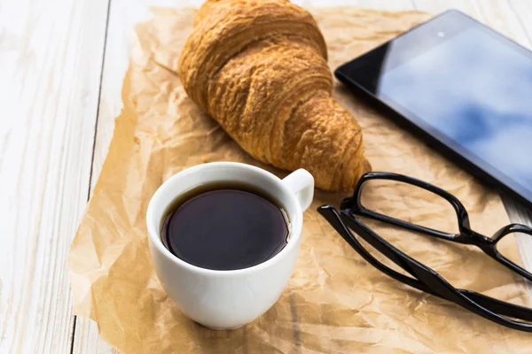 Croissant francés, vasos, taza de café y tableta — Foto de Stock