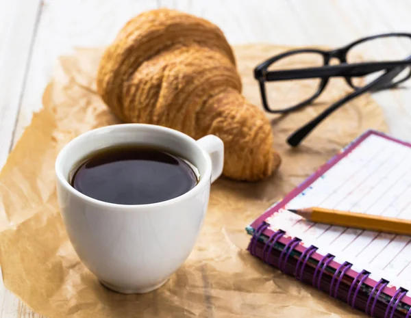Croissant francés, vasos, taza de café y cuaderno — Foto de Stock