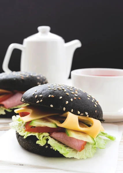 Hamburger noir, tasse de thé et de lait pour le petit déjeuner . — Photo