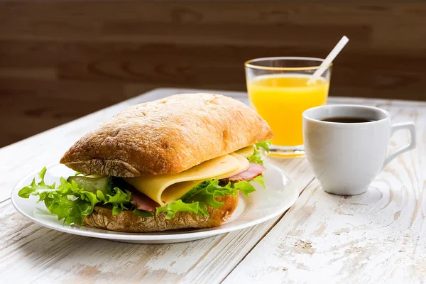 Chiabatta σάντουιτς, φλιτζάνι καφέ και πορτοκαλί χυμό — Φωτογραφία Αρχείου
