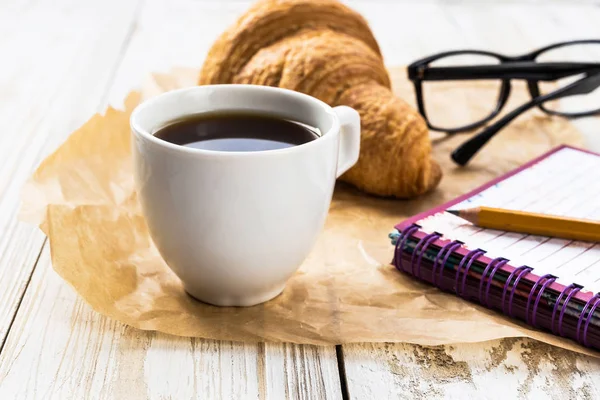 Croissant francés, vasos, taza de café y cuaderno — Foto de Stock