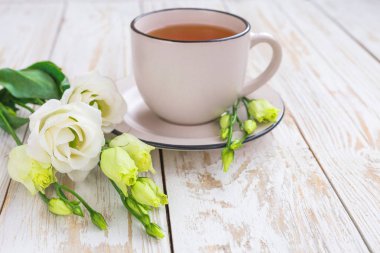 Fincan sıcak çay ve beyaz eustoma çiçek