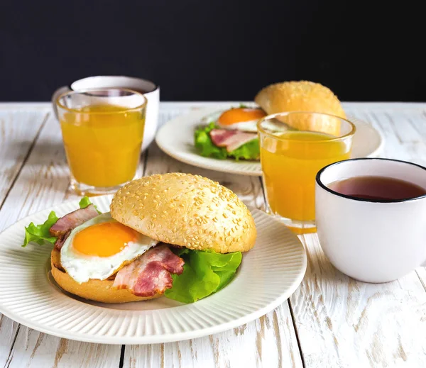 Burger sandwich, cup of tea and orange juice for breakfast