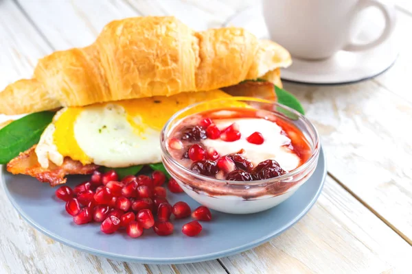 Fresh croissant sandwich, homemade yogurt, pomegranate and tea