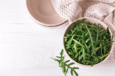 Ahşap masa üzerinde kase taze yeşil roka. 