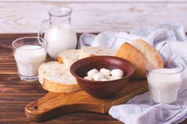 Dilimlenmiş kepekli ekmek, bardak taze süt ve mozzarella peyniri
