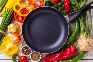 Çeşitli sebze malzemelerin üzerine ahşap masa etrafında kızartma tavası