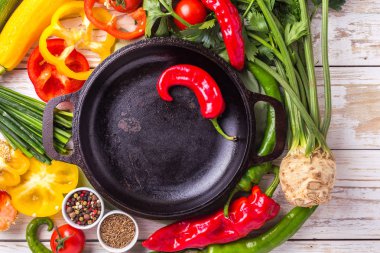 Çeşitli sebze malzemelerin üzerine ahşap masa etrafında kızartma tavası