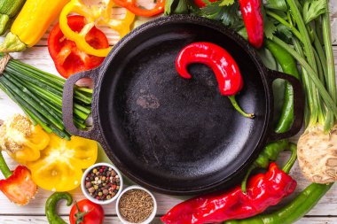 Çeşitli sebze malzemelerin üzerine ahşap masa etrafında kızartma tavası