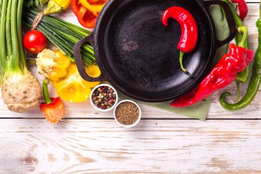 Çeşitli sebze malzemelerin üzerine ahşap masa etrafında kızartma tavası