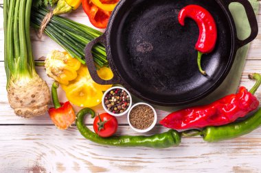 Çeşitli sebze malzemelerin üzerine ahşap masa etrafında kızartma tavası