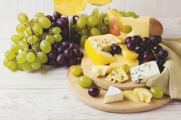 Cheese plate served with wine, fresh grapes and pears