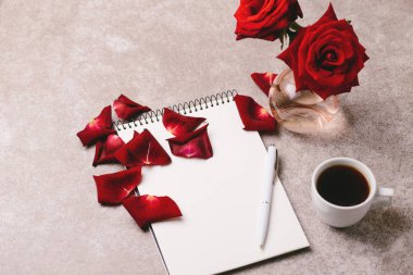 Defter, kalem, kırmızı gül ve kahve. Çalışma alanı. Üstten Görünüm