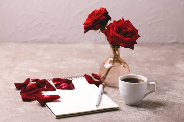 Defter, kalem, kırmızı gül ve kahve. Çalışma alanı. Yatay görünüm