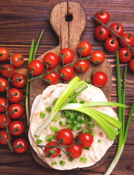 Indiska chapati, grön lök, körsbär tomat. Ovanifrån, flatlay. — Stockfoto