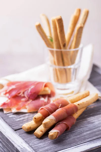 Traditional italian bread sticks grissini with prosciutto ham — Stock Photo, Image