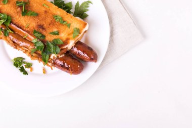 Fransız çörekleri ve karamelli soğanlı duble sosisli sandviç. Üstü mayonez sosu ve ketçapla kaplı..